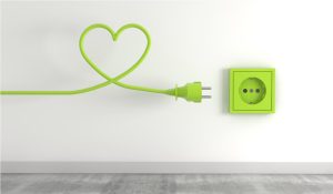 A yellow power cable arranged in the shape of a heart. A yellow power socket on a wall